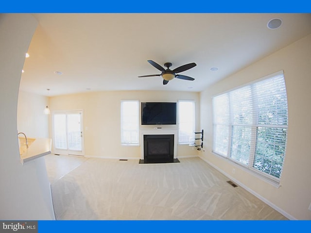 unfurnished living room with plenty of natural light, a fireplace with flush hearth, baseboards, carpet flooring, and recessed lighting