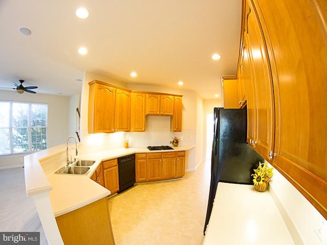 kitchen with brown cabinetry, a sink, black appliances, a peninsula, and recessed lighting