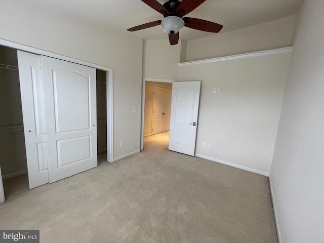 unfurnished bedroom featuring baseboards, light colored carpet, ceiling fan, and a closet
