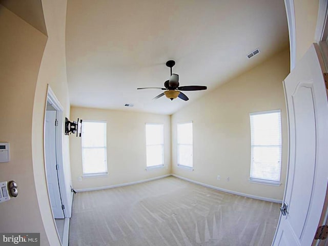 unfurnished room featuring baseboards, a ceiling fan, light colored carpet, and visible vents