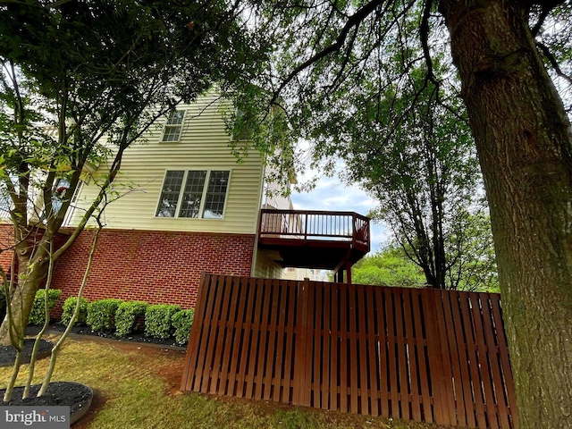 back of house with fence, a wooden deck, and brick siding