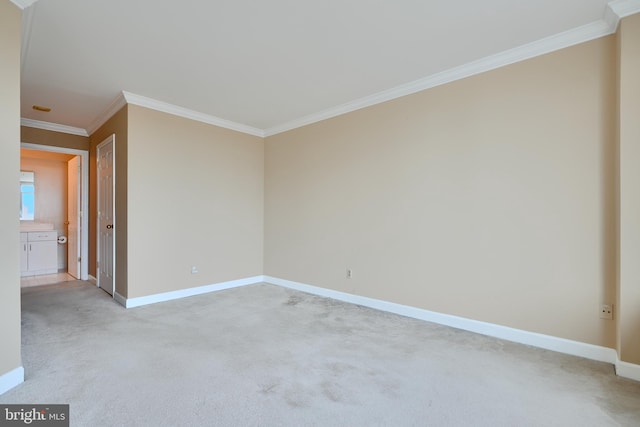 empty room featuring ornamental molding, baseboards, and light colored carpet
