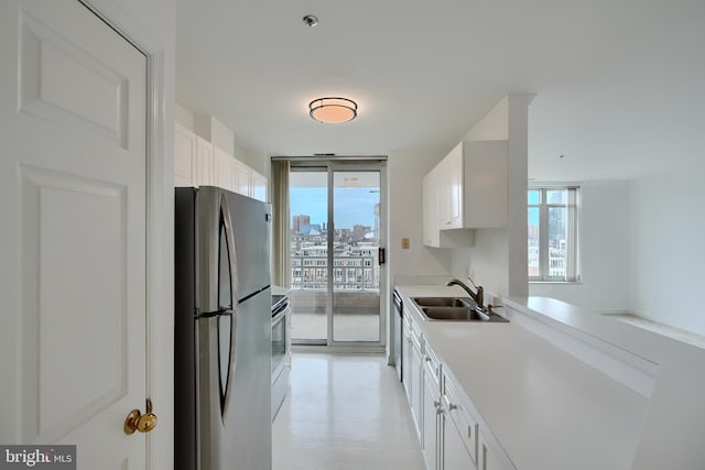 kitchen featuring stainless steel appliances, a sink, white cabinets, and light countertops