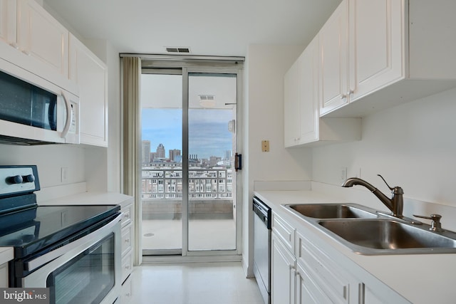 kitchen with appliances with stainless steel finishes, a sink, white cabinets, and a skyline view