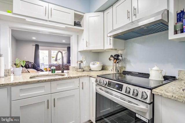 kitchen with light stone counters, white cabinetry, under cabinet range hood, stainless steel electric stove, and a sink