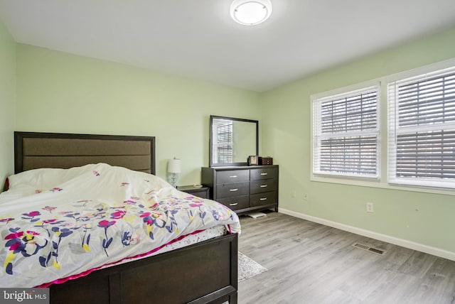 bedroom featuring visible vents, baseboards, and wood finished floors
