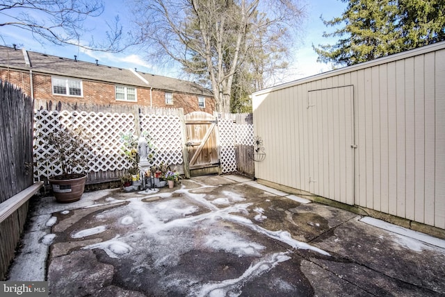 view of patio / terrace featuring an outbuilding, fence, a gate, and a storage unit