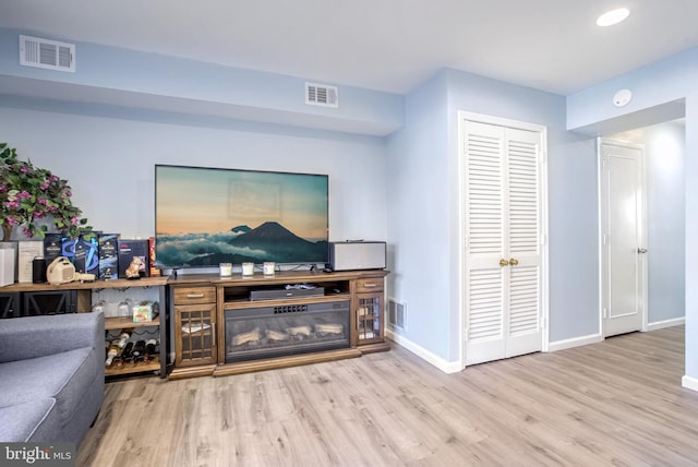 living area with wood finished floors, baseboards, and visible vents
