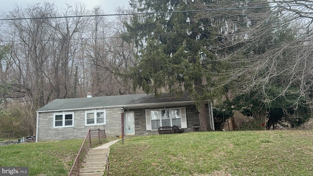 view of front of property with a front lawn, a chimney, and stone siding