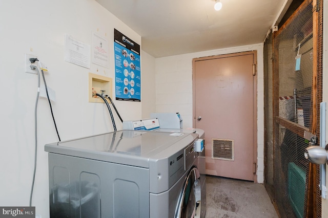 common laundry area with visible vents, washer and dryer, and concrete block wall
