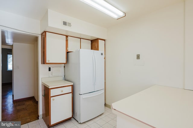 kitchen featuring freestanding refrigerator, light countertops, light tile patterned flooring, and visible vents
