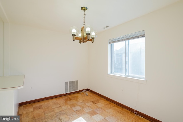 spare room with baseboards, visible vents, and a notable chandelier
