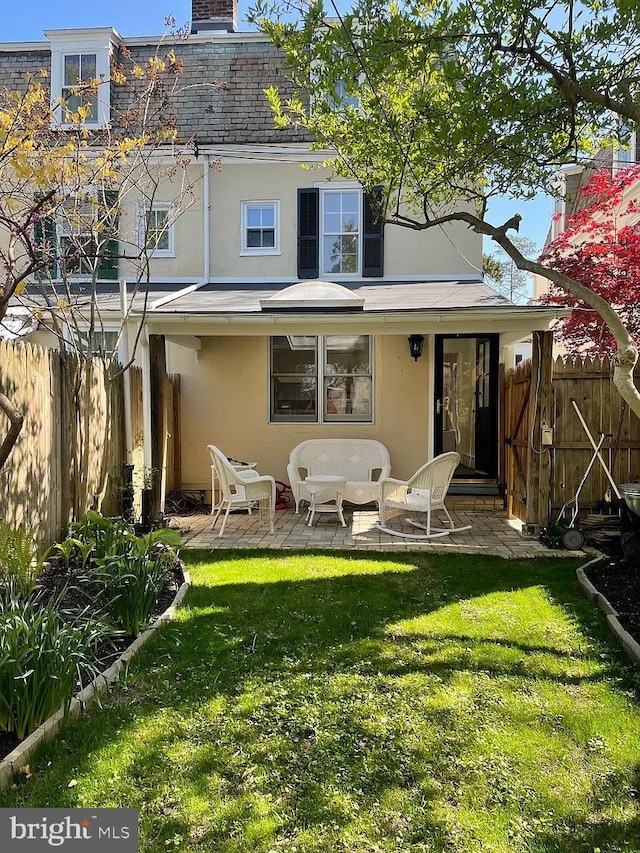 rear view of property with a yard, fence, stucco siding, and a chimney