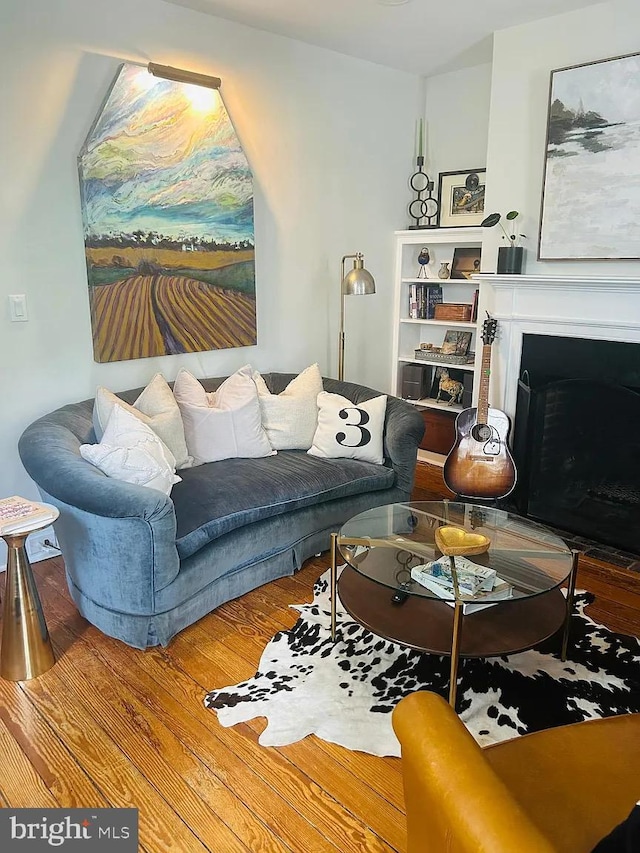 living area with a fireplace with flush hearth and wood finished floors
