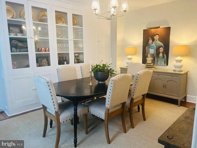 dining area with light wood finished floors and an inviting chandelier
