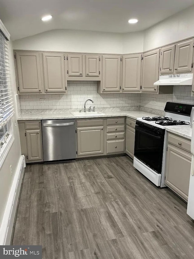 kitchen featuring a sink, a baseboard heating unit, under cabinet range hood, range with gas stovetop, and stainless steel dishwasher
