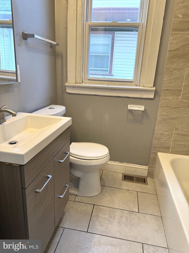 full bath featuring tile patterned flooring, vanity, a tub, toilet, and visible vents