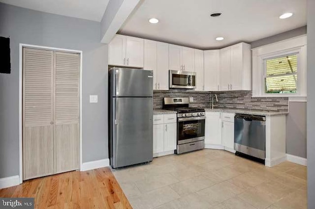 kitchen featuring baseboards, recessed lighting, appliances with stainless steel finishes, white cabinetry, and backsplash