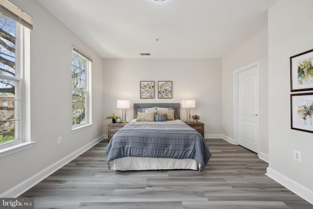 bedroom with wood finished floors, visible vents, and baseboards