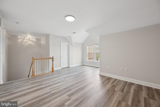 unfurnished room featuring lofted ceiling, wood finished floors, visible vents, and baseboards