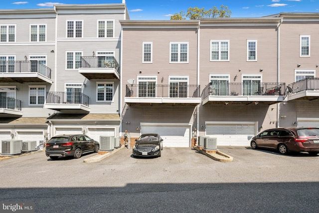 back of property featuring central AC, an attached garage, and driveway