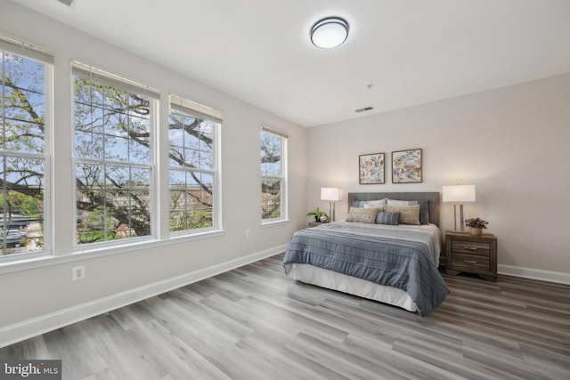 bedroom with baseboards, wood finished floors, and visible vents