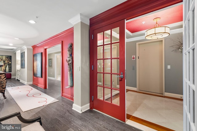 corridor featuring french doors, crown molding, baseboards, and wood finished floors