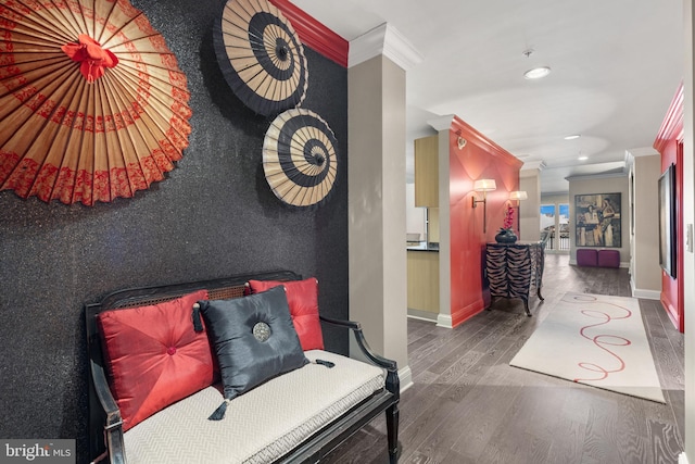 hall with baseboards, ornamental molding, wood finished floors, and an accent wall