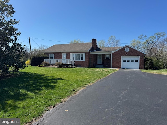 ranch-style house featuring a chimney, a front lawn, an attached garage, aphalt driveway, and brick siding