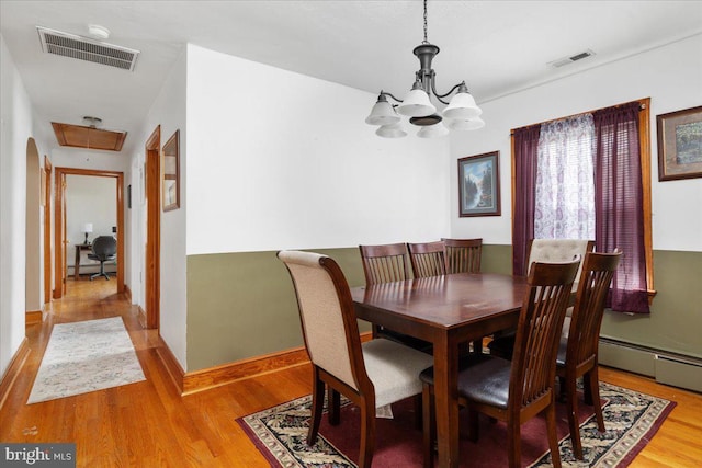 dining room featuring visible vents, light wood finished floors, arched walkways, and an inviting chandelier