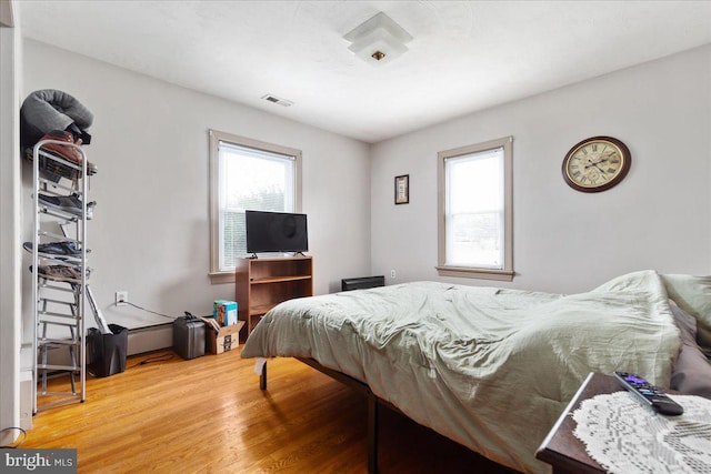 bedroom with wood finished floors, multiple windows, and visible vents