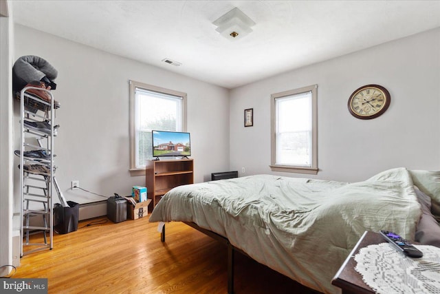 bedroom with visible vents, multiple windows, and wood finished floors