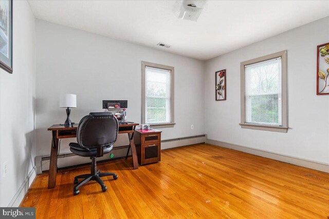 home office with visible vents, baseboards, light wood finished floors, and baseboard heating