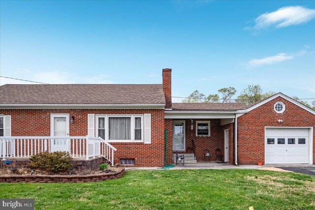 ranch-style house featuring an attached garage, a chimney, a front yard, and brick siding