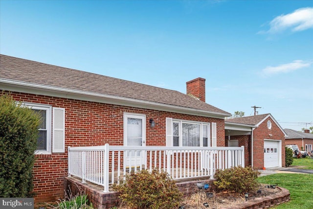 exterior space featuring a garage, a porch, brick siding, a chimney, and a shingled roof