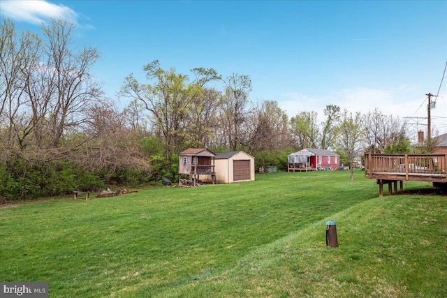 view of yard featuring a shed, a deck, an outdoor structure, and a detached garage