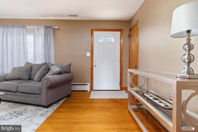 foyer with a wealth of natural light, light wood finished floors, baseboard heating, and visible vents