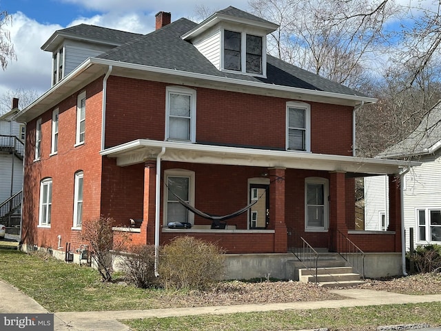 traditional style home featuring covered porch, brick siding, and roof with shingles