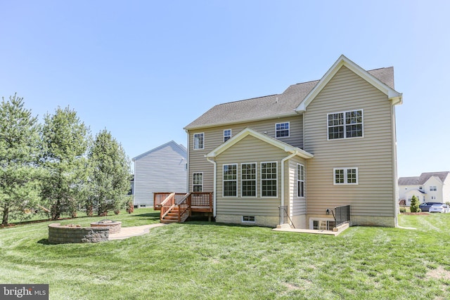 back of property with a yard, an outdoor fire pit, and a deck