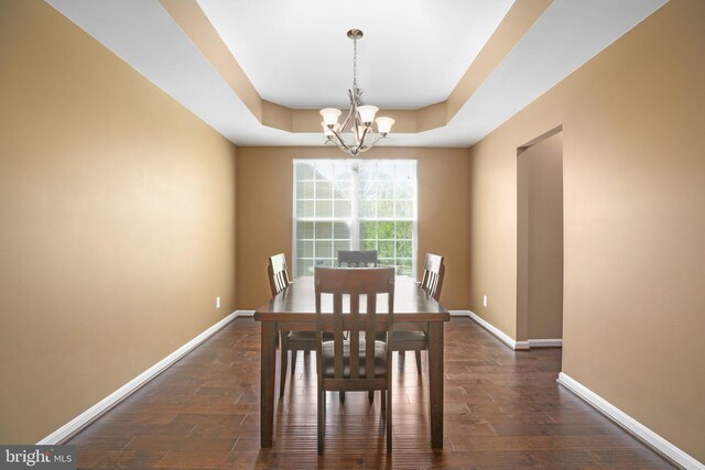dining area featuring dark wood-style floors, baseboards, an inviting chandelier, and a raised ceiling