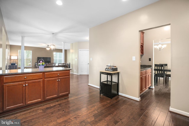 kitchen featuring a chandelier, open floor plan, brown cabinetry, and dark wood finished floors