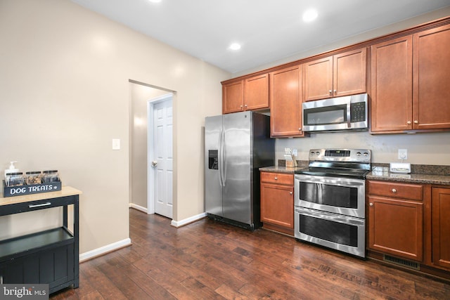kitchen featuring dark wood finished floors, baseboards, brown cabinetry, and appliances with stainless steel finishes