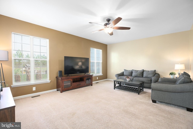 living area with visible vents, light colored carpet, a ceiling fan, and a healthy amount of sunlight