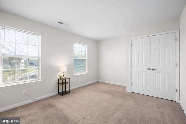 unfurnished bedroom with visible vents, a closet, baseboards, and carpet floors