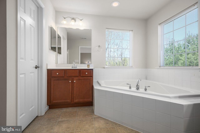full bathroom featuring recessed lighting, plenty of natural light, vanity, and a garden tub