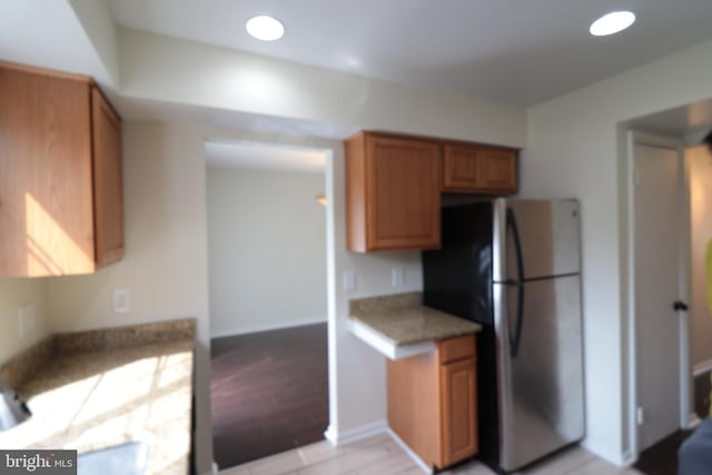kitchen with freestanding refrigerator, light countertops, light wood-style floors, and brown cabinetry