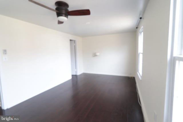 unfurnished room featuring dark wood-style flooring, a wealth of natural light, and ceiling fan