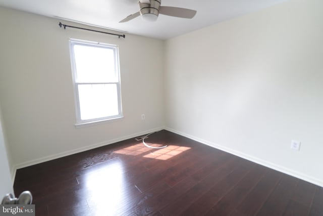 empty room with baseboards, dark wood-style floors, and a ceiling fan