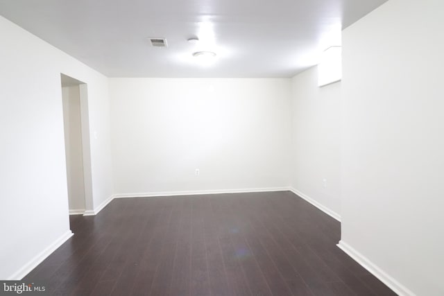 basement with dark wood-style flooring, baseboards, and visible vents