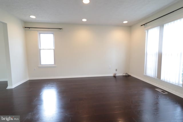 unfurnished room with baseboards, dark wood-style floors, visible vents, and recessed lighting